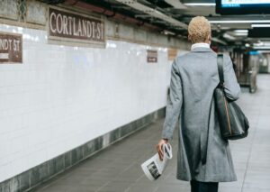 Professionally dressed women in a grey trench coat with her back to the camera walking away Image: Pexels/Ono Kosuki